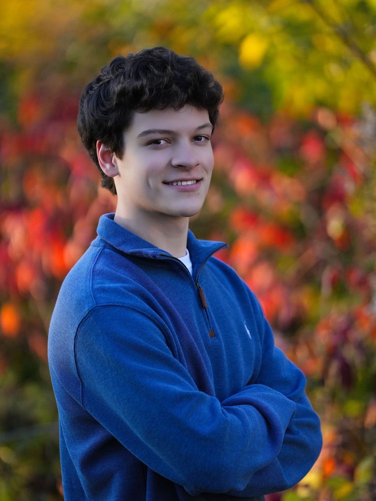 Young man smiling in front of autumn leaves